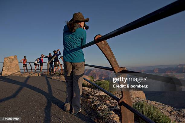 Visitor takes a photograph from Hopi Point at sunrise in Grand Canyon National Park in Grand Canyon, Arizona, U.S., on Thursday, June 25, 2015. The...