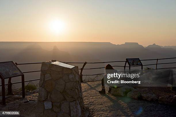 Visitor looks out from Hopi Point at sunrise in Grand Canyon National Park in Grand Canyon, Arizona, U.S., on Thursday, June 25, 2015. The Grand...