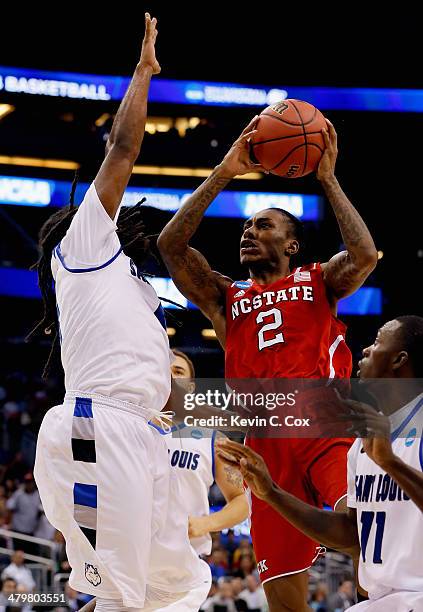 Anthony Barber of the North Carolina State Wolfpack drives in the first half against Jordair Jett and Mike McCall Jr. #11 of the Saint Louis...