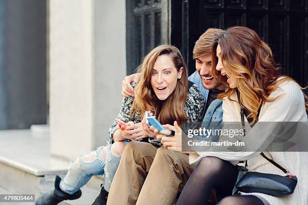 group of friends texting on smartphones - awe expression stock pictures, royalty-free photos & images