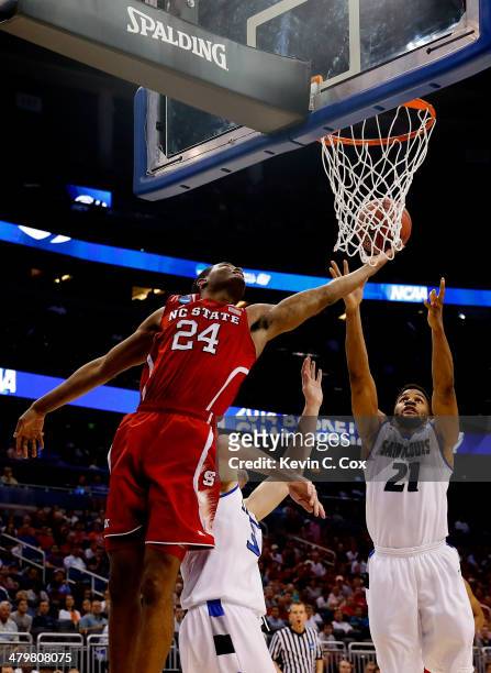 Warren of the North Carolina State Wolfpack shoots in the first half against Jake Barnett and Dwayne Evans of the Saint Louis Billikens against...