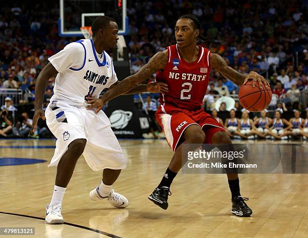 Anthony Barber of the North Carolina State Wolfpack dribbles against Mike McCall Jr. #11 of the Saint Louis Billikens during the second round of the...