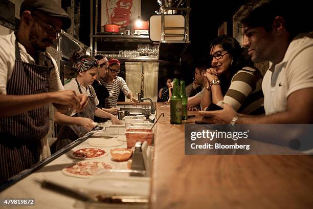 Patrons enjoy a drink and watch pizzas being made at the bar of Ferro & Farinha pizzeria in Rio de Janeiro, Brazil, on Thursday, July 2, 2015. The...