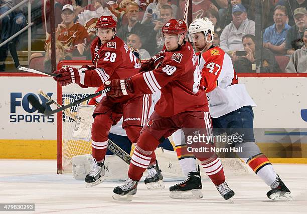 Mikkel Boedker of the Phoenix Coyotes attempts to knock down an airborne puck in front of Colby Robak of the Florida Panthers and teammate Lauri...