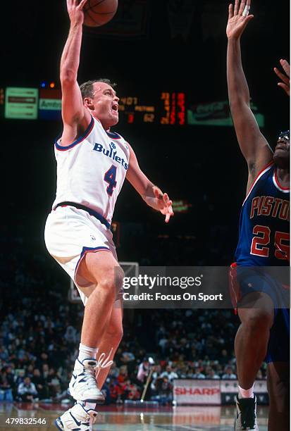 Scott Skiles of the Washington Bullets shoots over Oliver Miller of the Detroit Pistons during an NBA basketball game circa 1994 at the Capital...