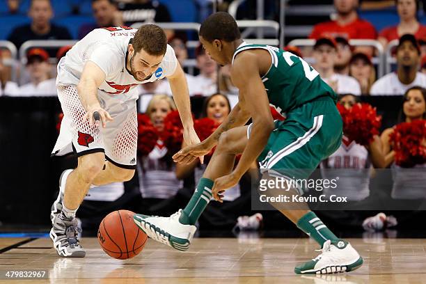George Beamon of the Manhattan Jaspers and Luke Hancock of the Louisville Cardinals go for a loose ball in the second half during the second round of...