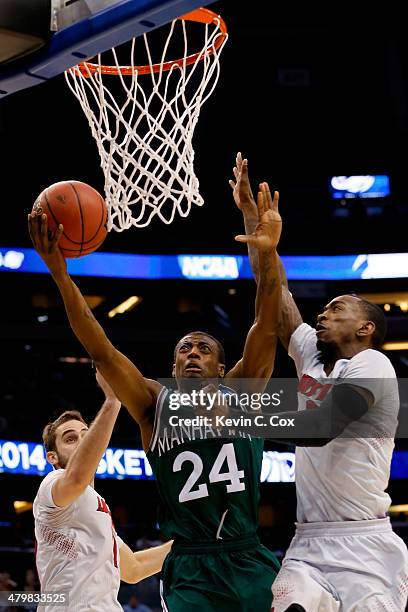 Luke Hancock and Russ Smith of the Louisville Cardinals defend George Beamon of the Manhattan Jaspers during the second round of the 2014 NCAA Men's...