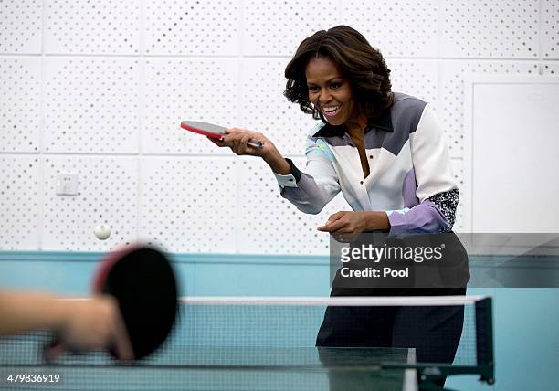 First lady Michelle Obama plays table tennis as she visit to the Beijing Normal School, a school that prepares students to attend university abroad,...