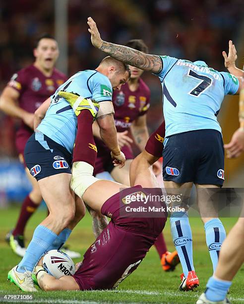 Trent Merrin and Trent Hodkinson of the Blues tackle Corey Parker of the Maroons in a dangerous tackle during game three of the State of Origin...