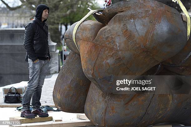 Chinese artist Liu Bolin attends the installation of his art creation, a giant fist sculpture "Iron First", at the Grand Palais museum in Paris on...