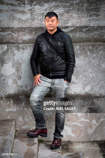 Chinese artist Liu Bolin poses before the installation of his art creation, a giant fist sculpture "Iron First", at the Grand Palais museum in Paris...