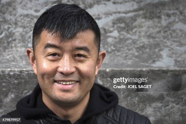 Chinese artist Liu Bolin poses before the installation of his art creation, a giant fist sculpture "Iron First", at the Grand Palais museum in Paris...