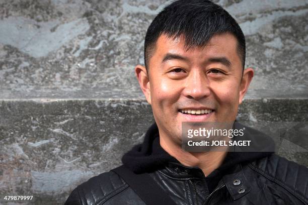 Chinese artist Liu Bolin poses before the installation of his art creation, a giant fist sculpture "Iron First", at the Grand Palais museum in Paris...