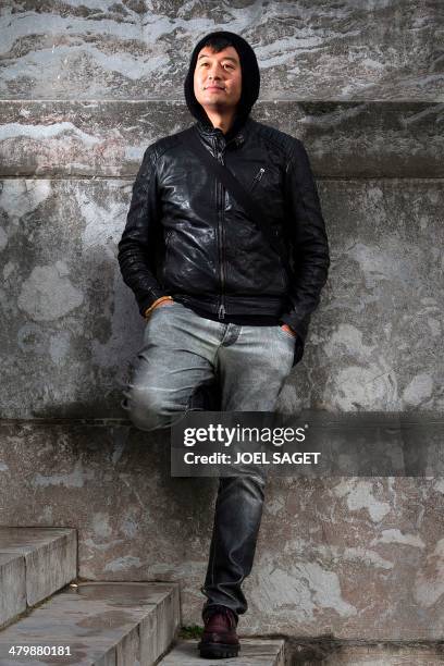 Chinese artist Liu Bolin poses before the installation of his art creation, a giant fist sculpture "Iron First", at the Grand Palais museum in Paris...