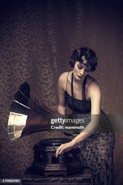 retro woman winding up a gramophone - picture of phonograph stock pictures, royalty-free photos & images