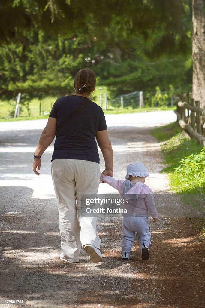 A grandmother and toddler  walking in the forest