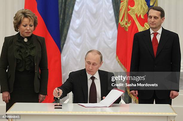 Russian President Vladimir Putin flanked by Upper House Speaker Valentina Matviyenko and State Duma Speacker Sergei Naryshkin signs final decree...