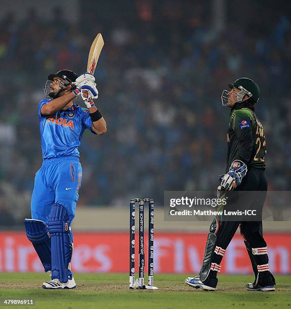 Virat Kohli of India hits a six, as Kamran Akmal of Pakistan looks on during the ICC World Twenty20 Bangladesh 2014 match between India and Pakistan...