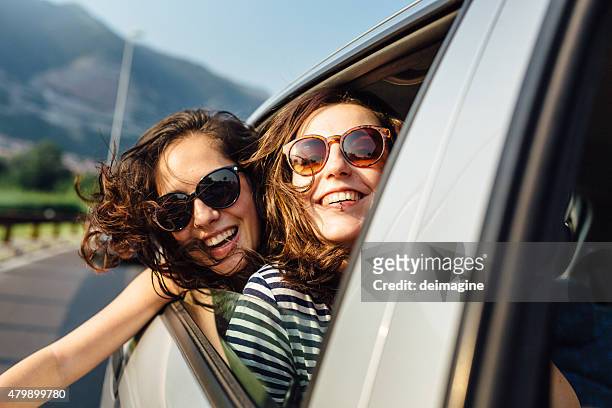 young women enjoying car trip, hair in the wind - couple in car smiling stock pictures, royalty-free photos & images