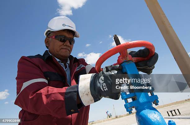 An oil worker adjusts the wheel of a flow valve on a modern oil pumping unit at an oilfield operated by Embamunaigas, a unit of KazMunaiGas...