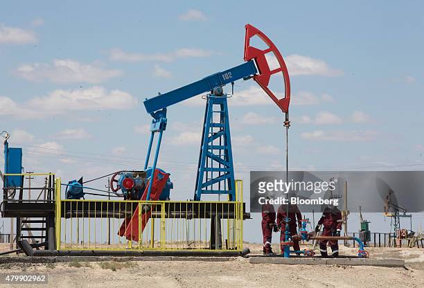 Workers perform maintenance on an oil pumping unit, also known as a "nodding donkey", at an oilfield operated by Embamunaigas, a unit of KazMunaiGas...