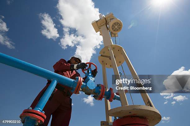 An oil worker adjusts the wheel of a flow valve on a modern oil pumping unit at an oilfield operated by Embamunaigas, a unit of KazMunaiGas...