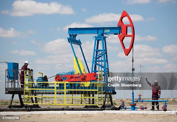 Workers perform maintenance on an oil pumping unit, also known as a "nodding donkey", at an oilfield operated by Embamunaigas, a unit of KazMunaiGas...