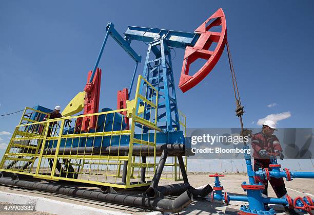 Workers perform maintenance on an oil pumping unit, also known as a "nodding donkey", at an oilfield operated by Embamunaigas, a unit of KazMunaiGas...