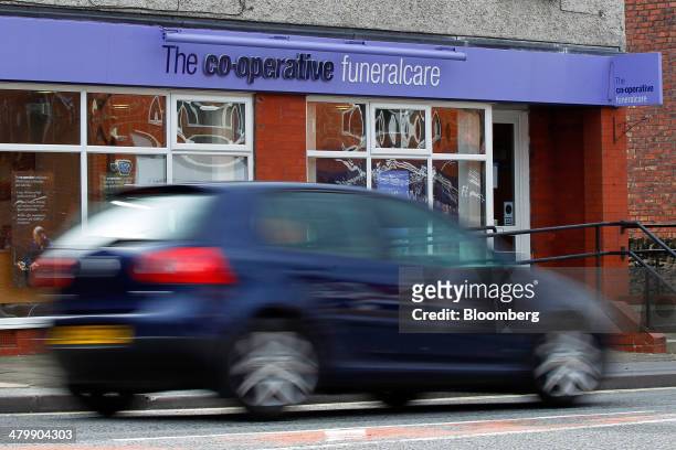 An automobile drives past a Co-Operative Funeralcare store, operated by the Co-Operative Group Ltd., in High Lane, U.K., on Thursday, March 20, 2014....