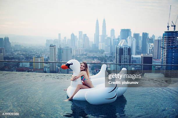 young woman in rooftop pool - rooftop pool stock pictures, royalty-free photos & images