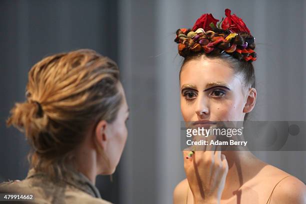 Stylist applies make-up to a model during the Rebekka Ruetz show at the Mercedes-Benz Fashion Week Berlin Spring/Summer 2016 at Brandenburg Gate on...
