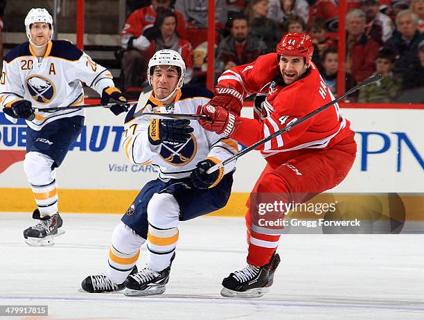 Matt D'agostinini of the Buffalo Sabres battles for a loose puck with Jay Harrison during their NHL game at PNC Arena on March 13, 2014 in Raleigh,...