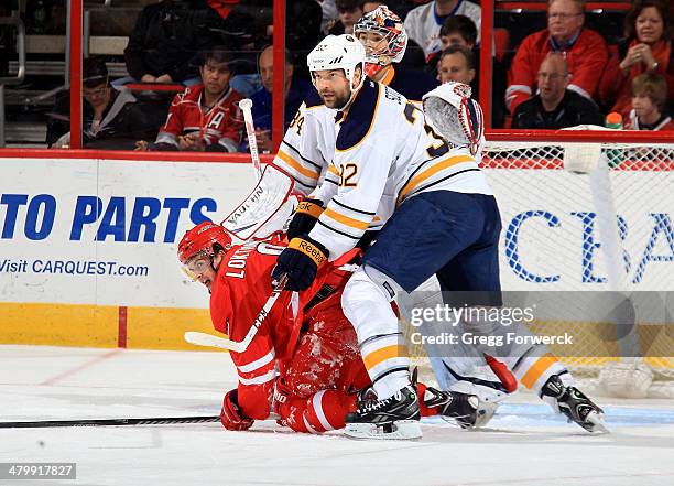 Andrei Loktionov of the Carolina Hurricanes battles in the crease with John Scott of the Buffalo Sabres during their NHL game at PNC Arena on March...