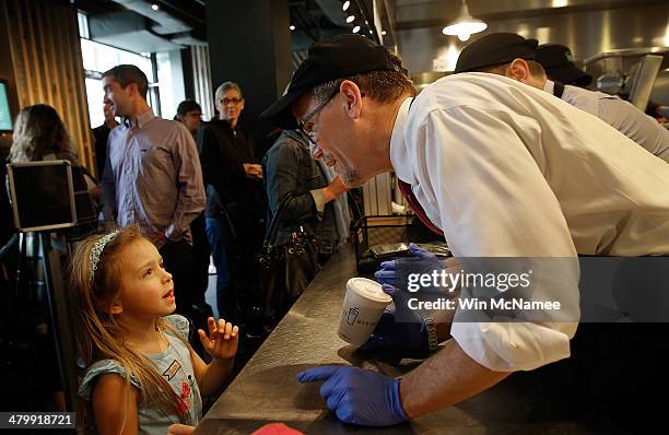 Labor Secretary Thomas Perez serves a strawberry milkshake to a young girl while touring the restaurant with Shake Shack CEO Randy Garutti March 21,...