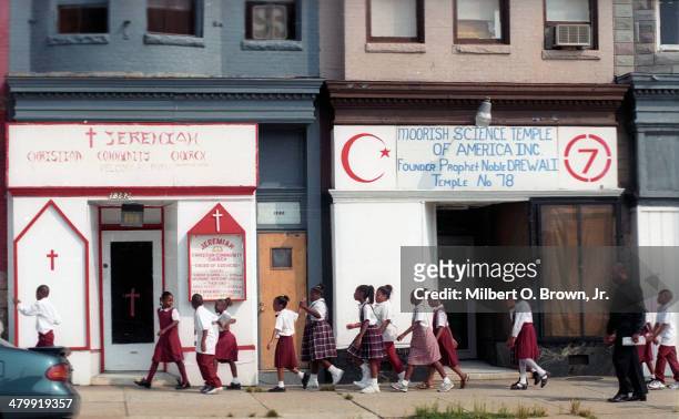 Group of uniformed school children walk west along W North Avenue , past a storefront church and a storefront temple , Baltimore, Maryland, October...