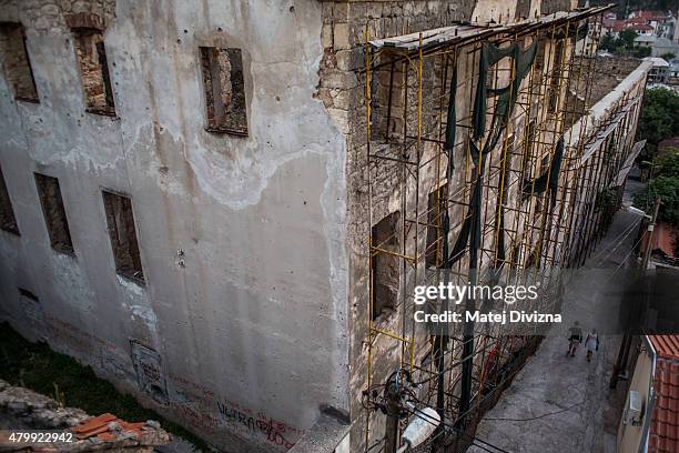Tourists walk past a building destroyed during Bosnian war on July 7, 2015 in Mostar, Bosnia and Herzegovina. The newly-identified remains of another...