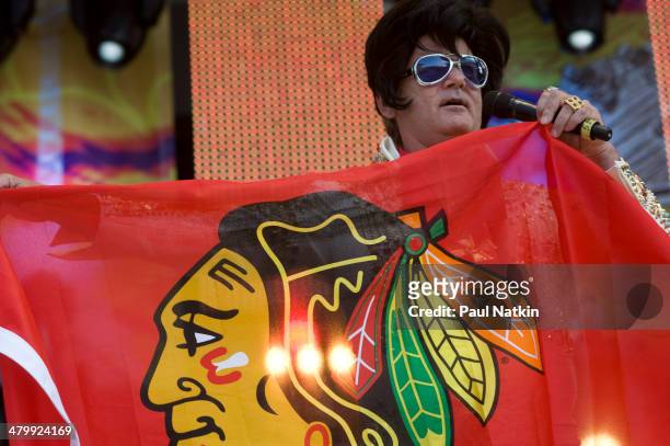Dressed as Elvis Presley, actor Bill Murray holds a Chicago Blackhawks hockey team banner as he performs onstage at Eric Clapton's Crossroads Guitar...