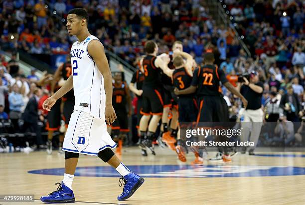 Quinn Cook of the Duke Blue Devils walks off the floor as the Mercer Bears celebrates after defeating the Duke Blue Devils 78-71 during the Second...