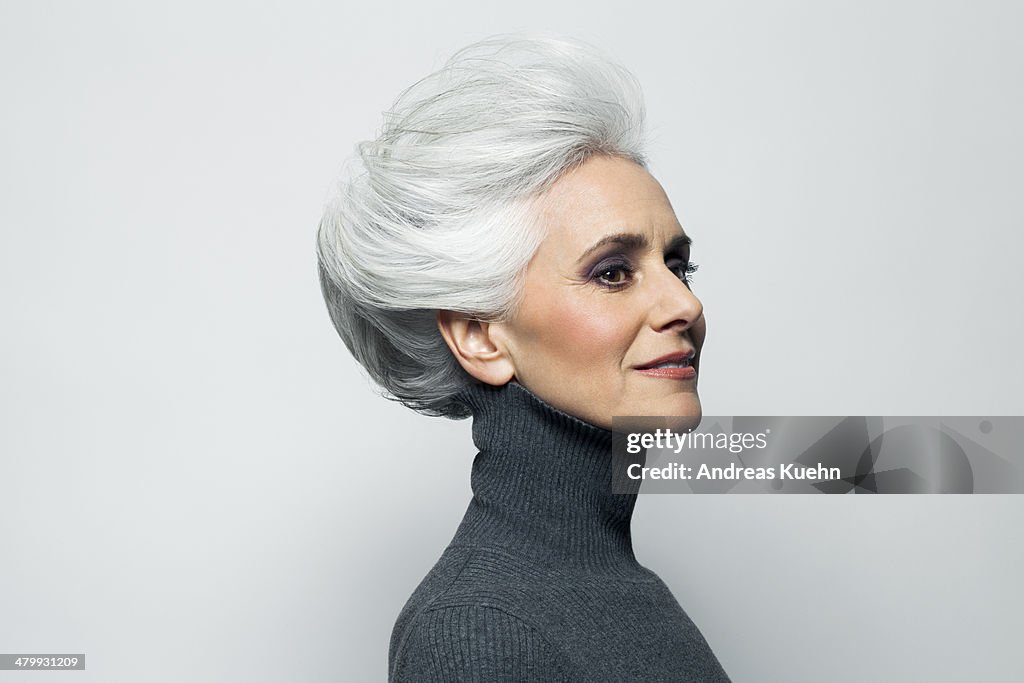 Grey haired woman in grey turtleneck sweater.