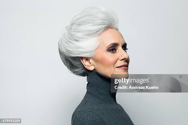 Grey haired woman in grey turtleneck sweater.