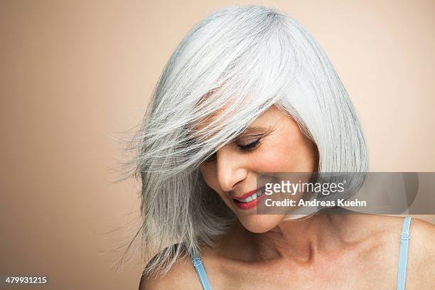 woman with a silvery,grey bob looking down. - kurzes haar dame stock-fotos und bilder