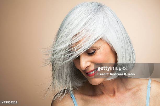 woman with a silvery,grey bob looking down. - short bob haircuts stock pictures, royalty-free photos & images