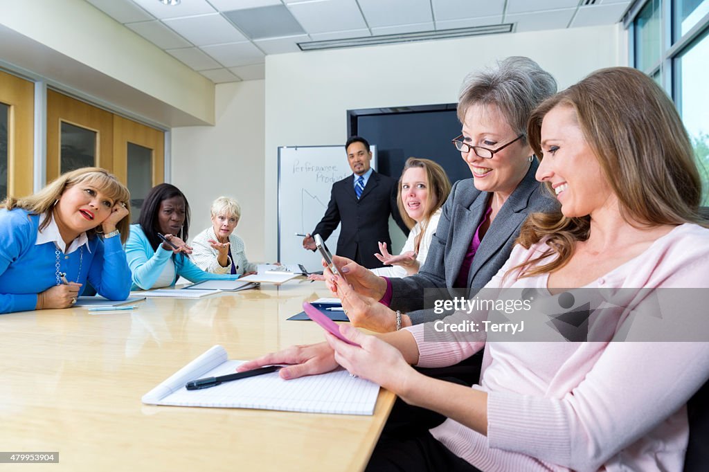 Two Women Look at Cell Phones at a Business Meeting