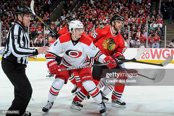 Andrei Loktionov of the Carolina Hurricanes and Michal Handzus of the Chicago Blackhawks battle for position near linesman Andy McElman during the...