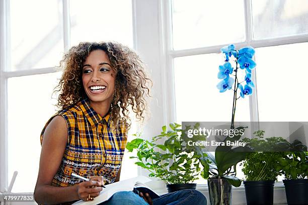 woman working surrounded by plants and flowers. - checked shirt stock-fotos und bilder