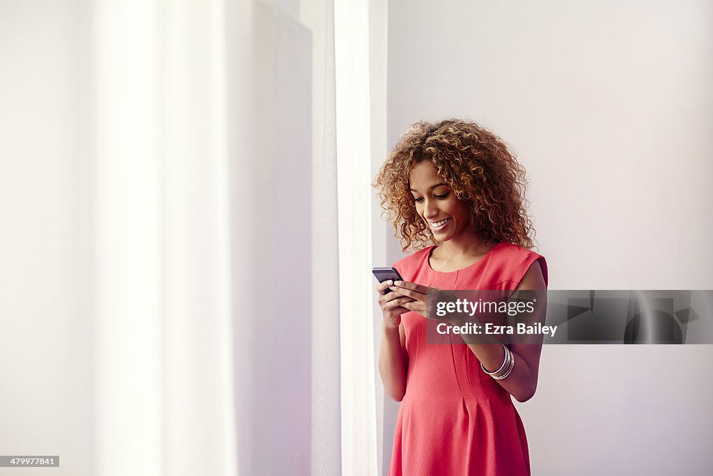 Mixed race woman using her phone at home