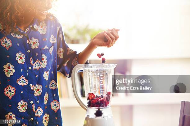 woman making a smoothie at home. - green berry smoothie stock pictures, royalty-free photos & images