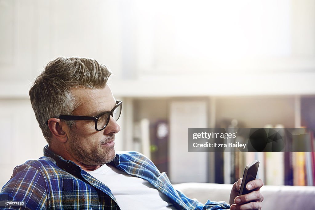 Man using his phone while relaxing at home.