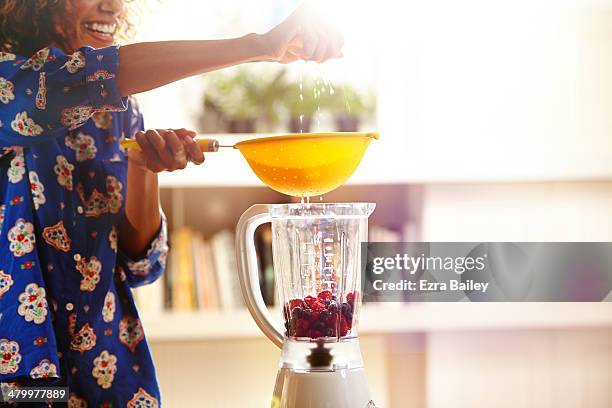 woman squeezing an orange while making a smoothie. - colander foto e immagini stock