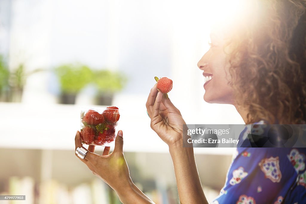 Woman eating strawberries at home.